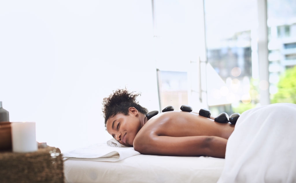 Reduce Stress - Shot of a young woman getting a hot stone massage at a spa