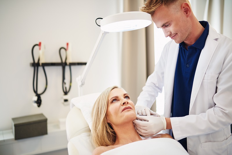 doctor injecting botox into a mature womans cheek YECRQV4