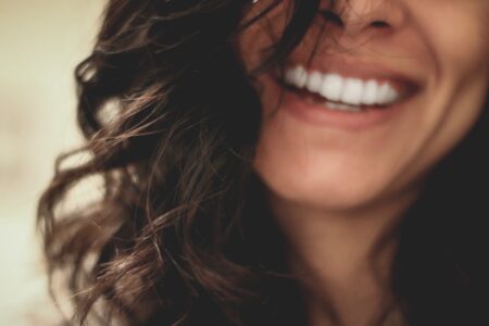 A woman with long wavy black hair smiling with visible white teeth