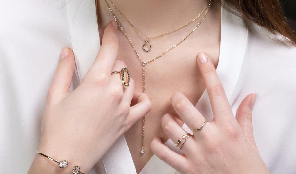 A woman trying to pick between different pieces of gold jewelry