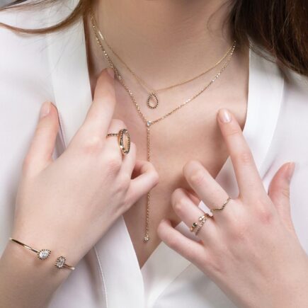 A woman trying to pick between different pieces of gold jewelry