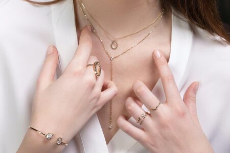 A woman trying to pick between different pieces of gold jewelry